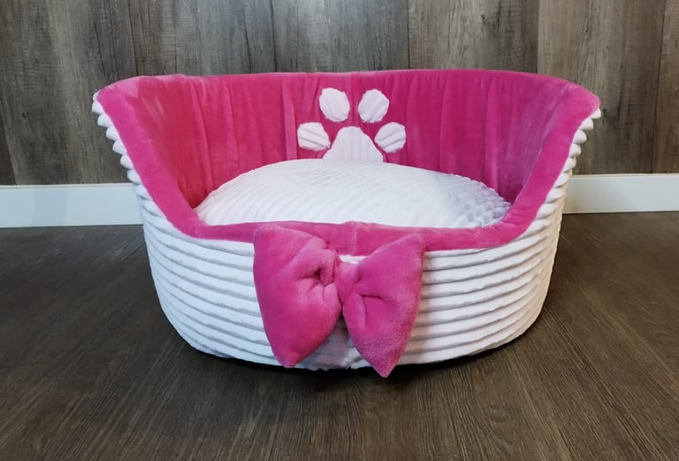 a dog bed with a pink bow tie and a pink bow